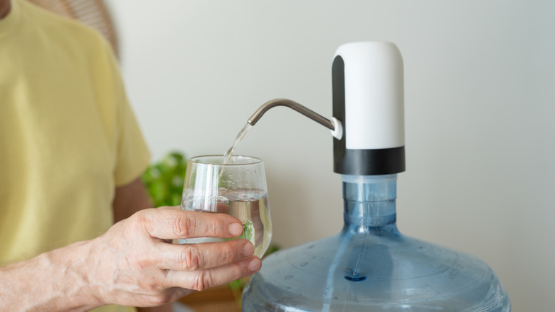 Système de filtration d'eau La personne verse de l'eau dans la tasse