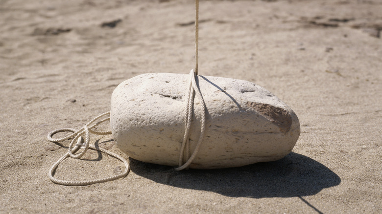 Une roche reposant sur la surface de sable est attachée avec une corde