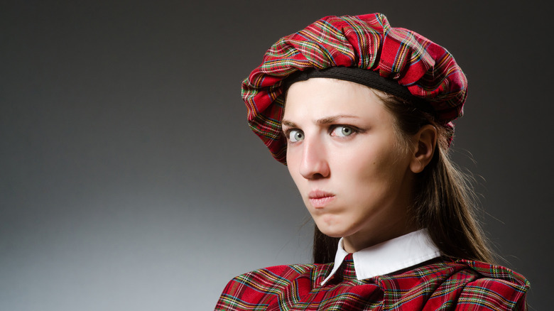 Une femme vêtue d'une tenue écossaise traditionnelle a l'air ennuyée