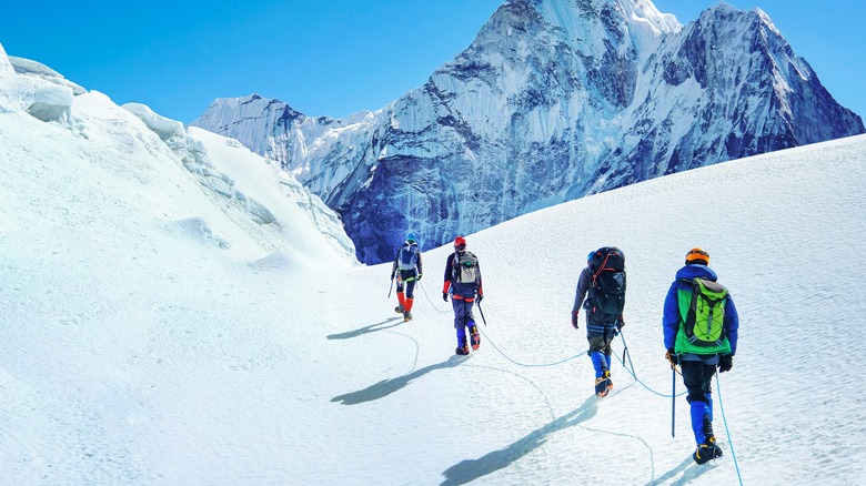 Équipe d'escalade en coin traversant la pente enneigée
