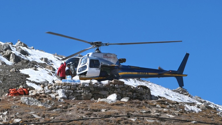 Les gens déchargent les fournitures d'un hélicoptère atterrissant dans un camp de base du mont Everest au Népal