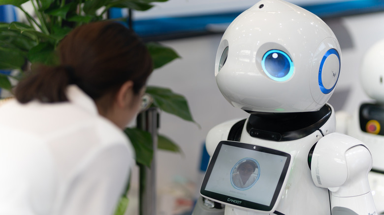 Une femme interagissant avec un robot de reconnaissance faciale