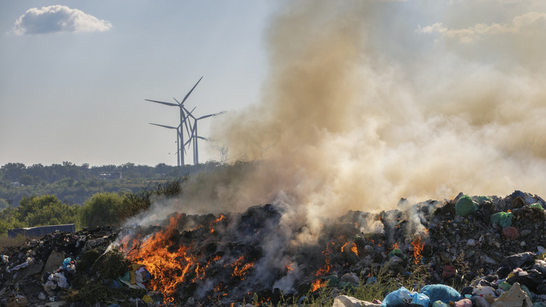 Décharge de déchets brûlant avec des panneaux solaires en arrière-plan