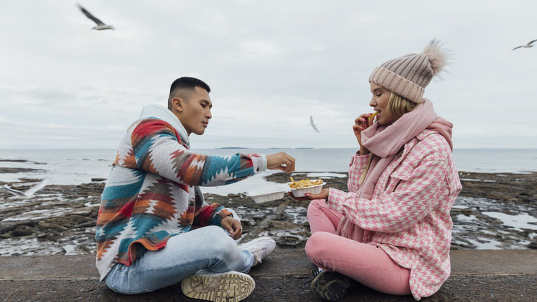 Couple profitant du repas pendant que les mouettes volent à proximité