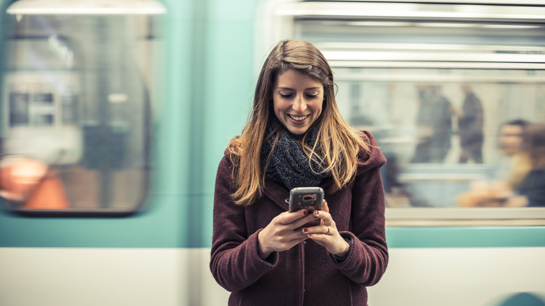 Femme qui regarde son téléphone dans le métro à Paris