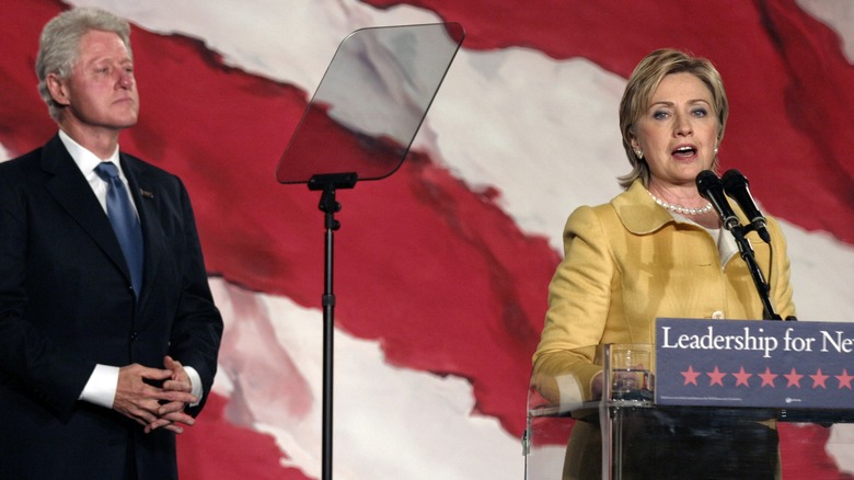 Bill Clinton debout derrière Hillary Clinton