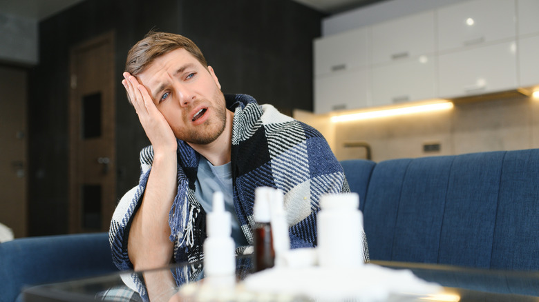 Homme malade assis devant une table pleine de médicaments