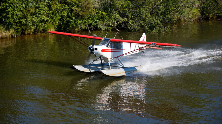 Un petit avion flottant privé décoller dans un cadre sauvage.
