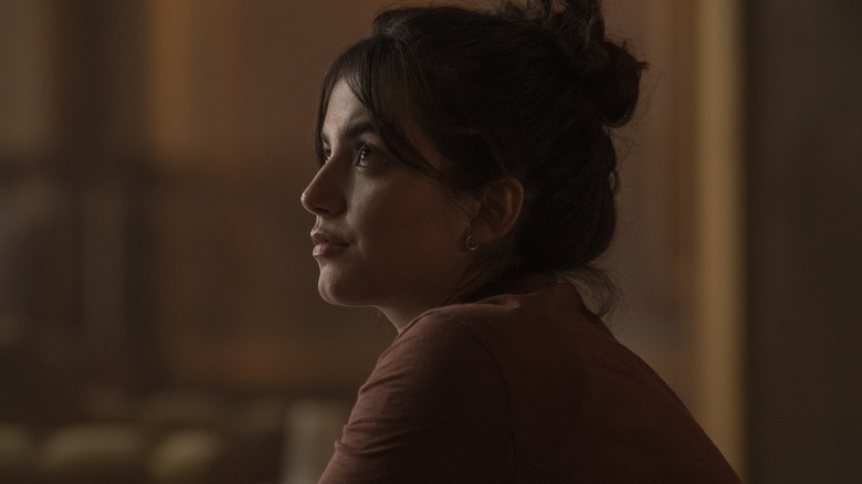 Dina avec ses cheveux en chignon levant les yeux sur le dernier de nous