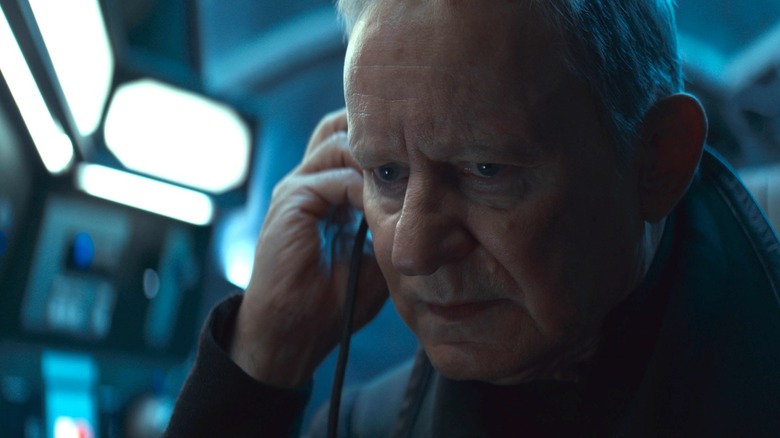 Stellan Skarsgård en tant que Luthen Rael tenant un écouteur et ayant l'air inquiet dans Andor Saison 2