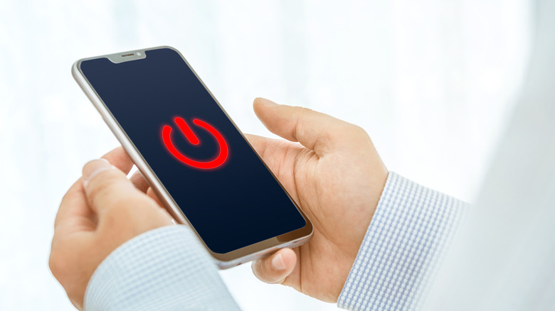 Icône d'alimentation sur le smartphone d'un homme.