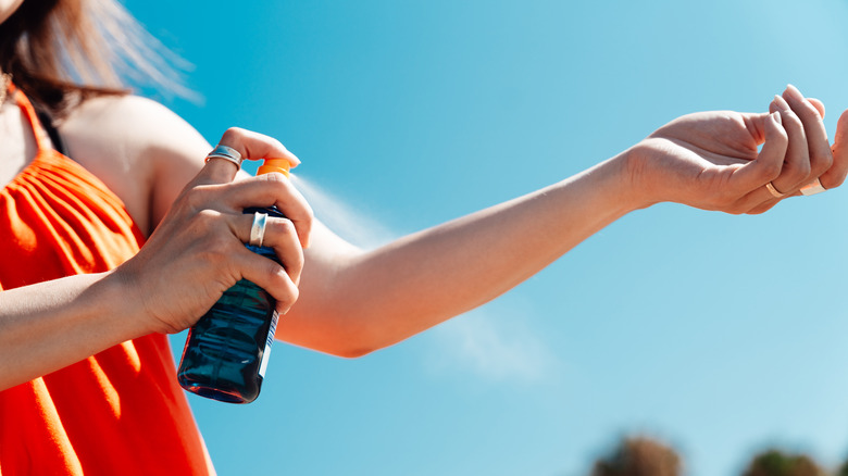 Femme appliquant un écran solaire sur le bras