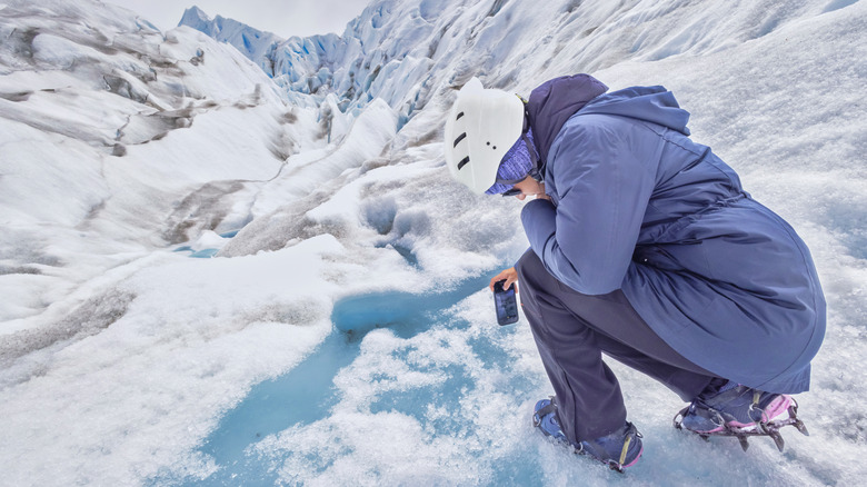 Femme prenant une photo de fonte glaciaire