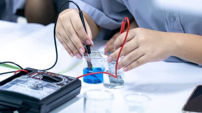 Expériences de chimiste avec des solutions d'électrolyte dans des béchers