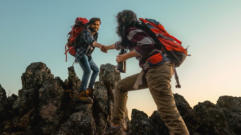 Deux randonneurs s'entraident sur des rochers déchiquetés