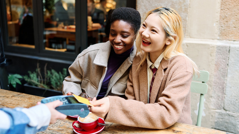Les voyageurs souriants paient dans un restaurant