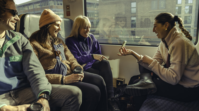 Une femme montre un téléphone à des amis dans un train