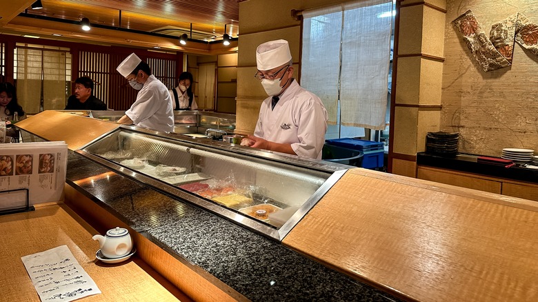 Des chefs de sushi se préparant derrière le comptoir