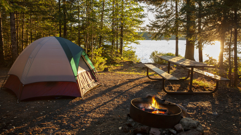 tente au camping en bois avec table de pique-nique et feu de camp
