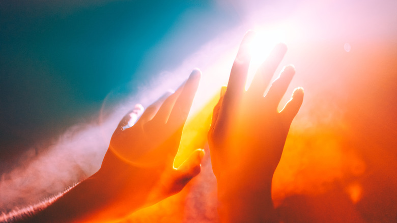 Les mains humaines se rapprochent d'un ciel rouge et orange