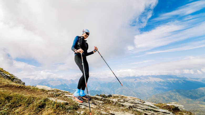 Randonneur heureux descendant dans les montagnes avec des poteaux de trekking