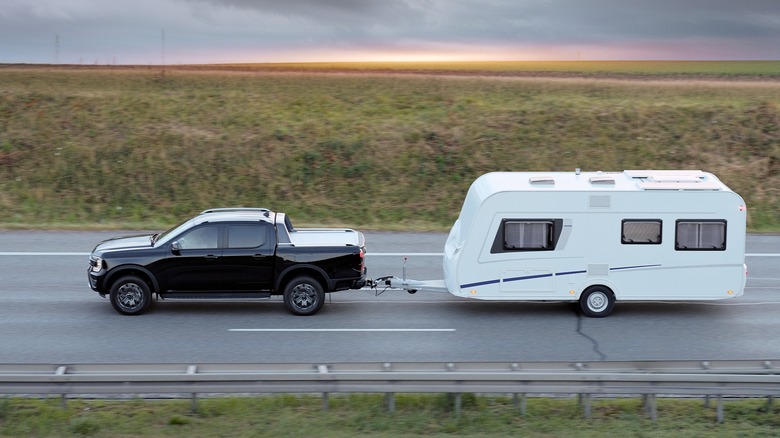 remorque de voyage remorquée derrière un camion au coucher du soleil