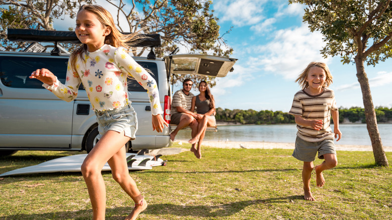 Un couple regarde leurs enfants courir à l'extérieur un jour d'été