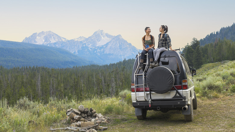 Deux amies assises sur un camping-car dans un parc forestier