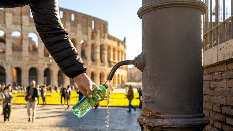 La personne remplit une bouteille d'eau à l'extérieur du colosseum