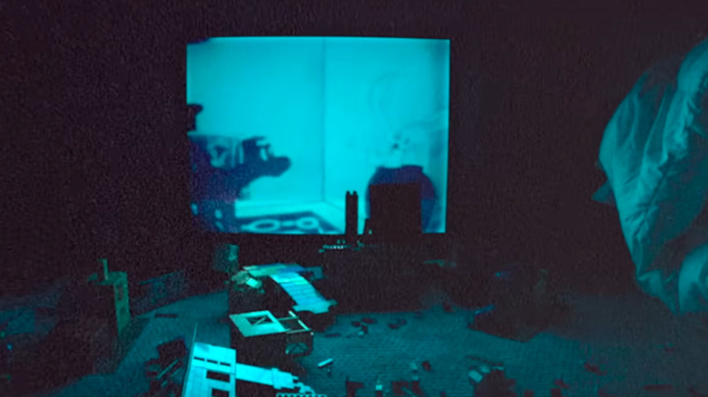 Jouets sur le sol devant une télévision brillante à Skinamarink