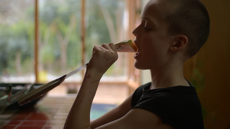 Oliver tenant un couteau de cuisine avec du cantaloup à l'extrémité