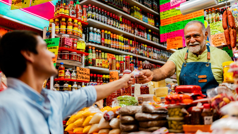Un homme tend un vendeur une note de peso sur un étal de marché au Mexique