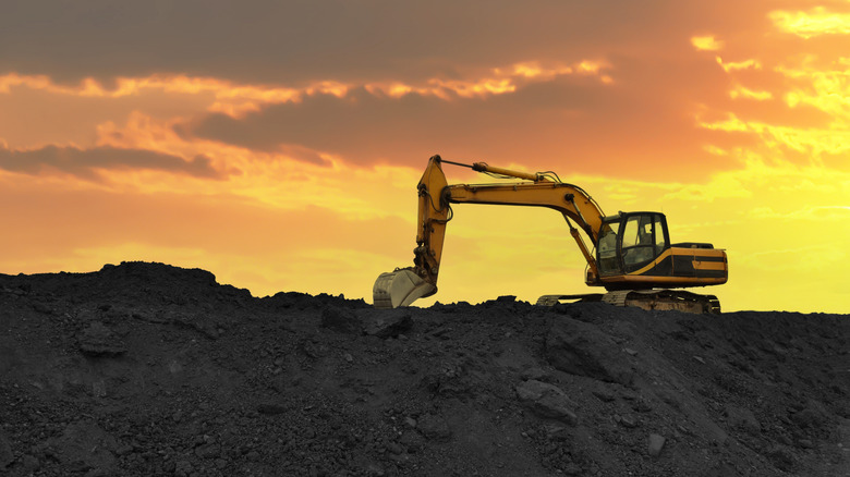 Une excavatrice au sommet d'une mine de lithium contre un ciel orange