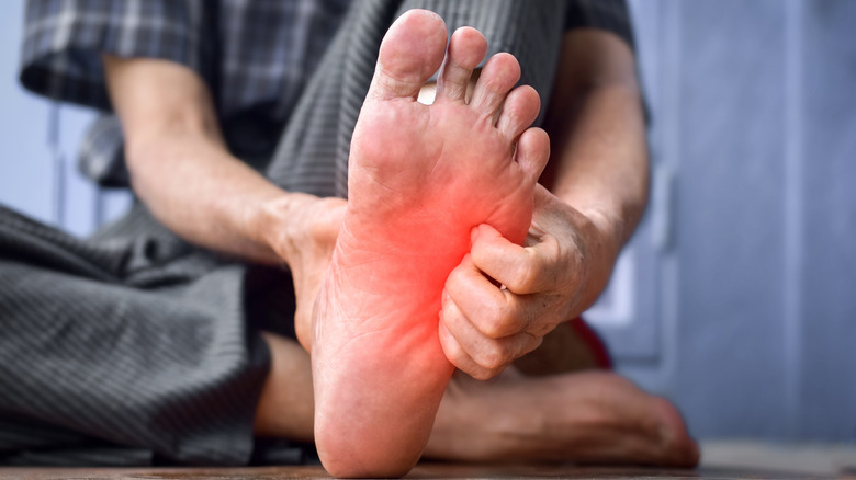 Un homme tient le pied après une piqûre