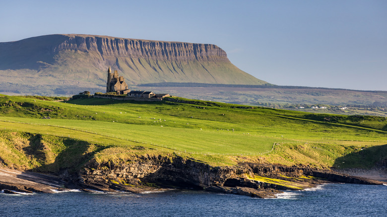 Green Fields menant à la mer avec une toile de fond d'un château et d'une montagne de table