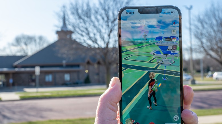 Application de jeu Pokemon Go sur un téléphone avec un gymnase défocalisé en arrière-plan.