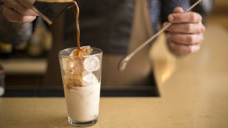 Barista versant l'esprisse avec une boisson glacée