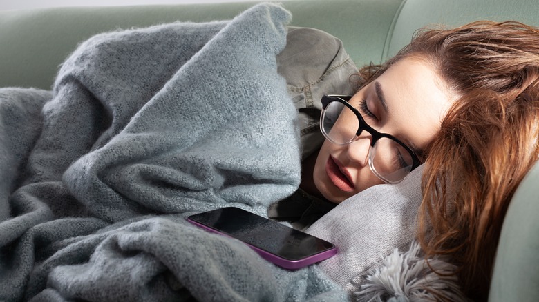 Personne endormie sur le canapé à côté du smartphone