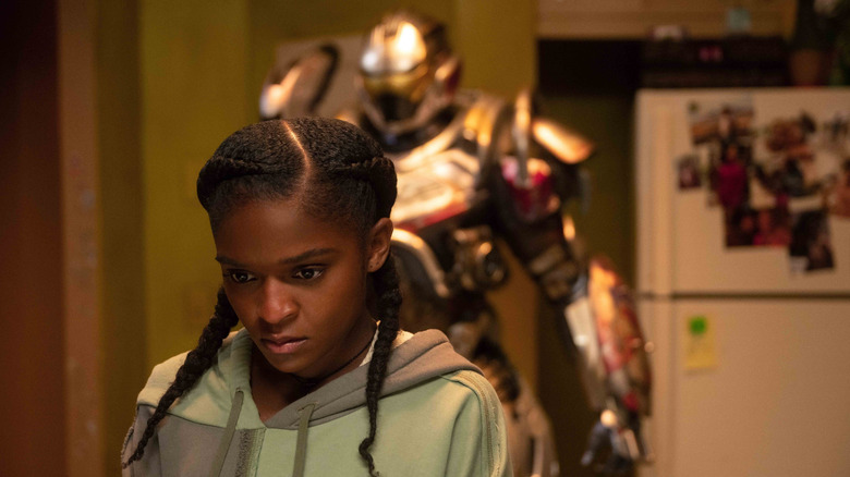 Dominique Thorne comme Riri Williams debout devant son armure dans sa cuisine à Ironheart