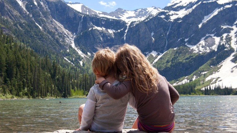 Deux enfants assis sur un rocher surplombant le lac Avalanche du parc national des glaciers