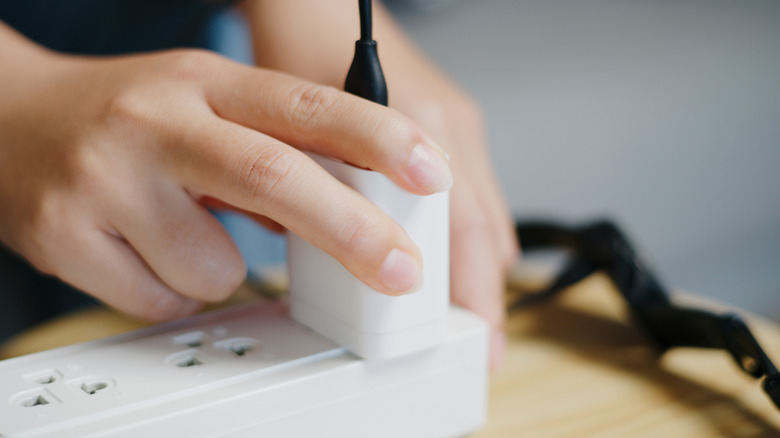 Une personne qui branche le chargeur de téléphone à la rallonge