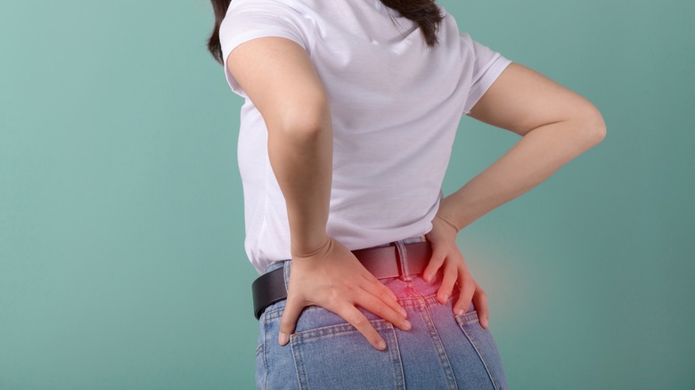 Une femme le tient le bas dans la douleur sur un fond vert