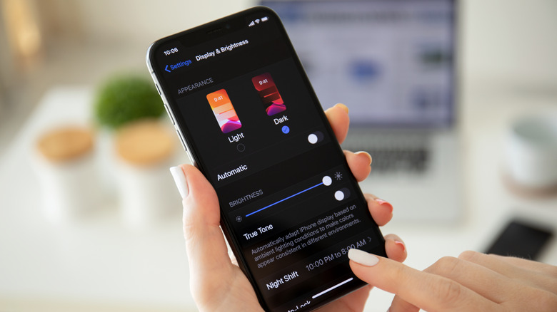 Une personne configurant les paramètres d'affichage et de luminosité sur son iPhone