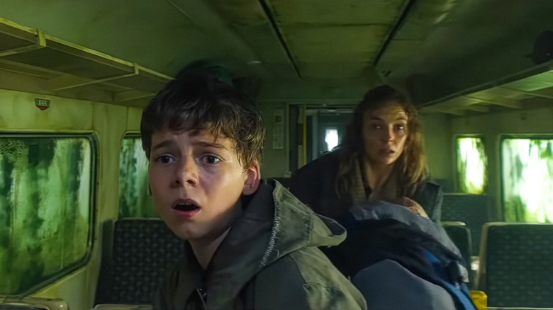 28 ans plus tard, Isla tenant bébé Isla dans le train, debout derrière Spike