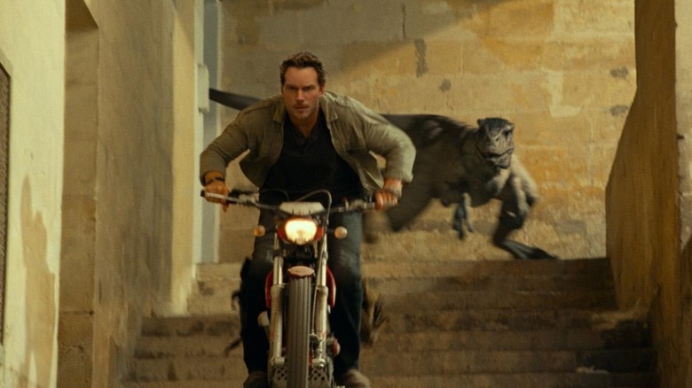 Chris Pratt comme Owen Grady éloignant sa moto de l'atrociraptor de Jurassic World Dominion