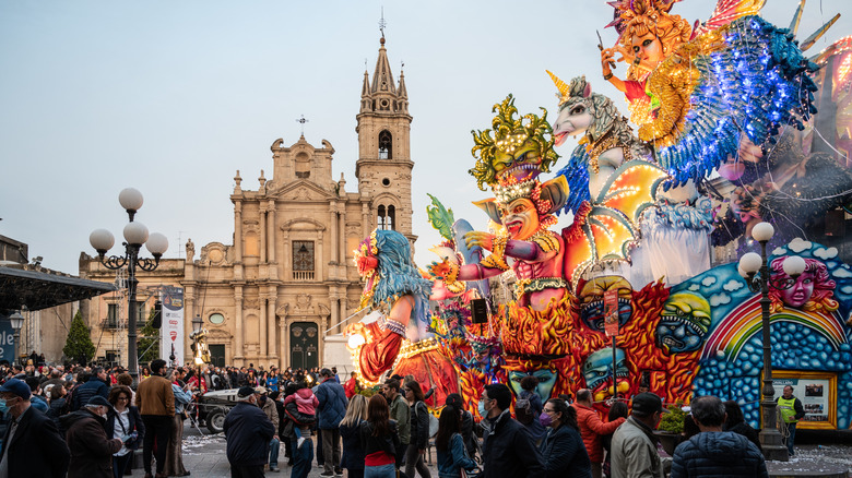 Des marionnettes géantes vives et des flotteurs de parade devant une église baroque à ACIREALE