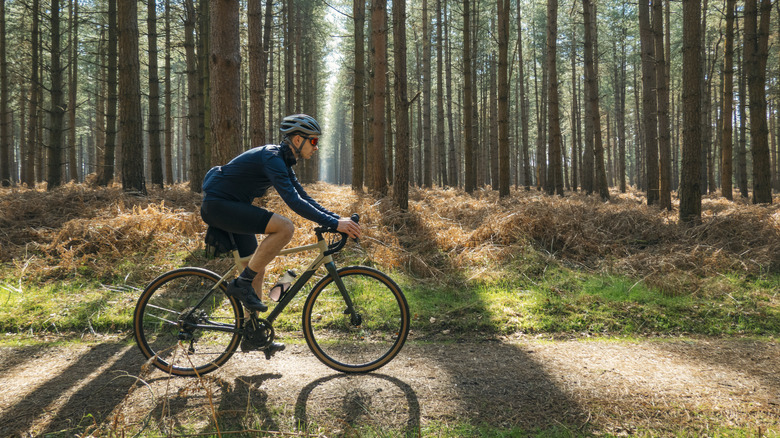 Un homme fait le vélo sur un parcours du vélo au soleil du matin