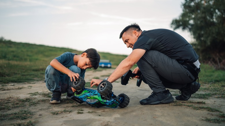 Papa joyeux regardant son fils jouer avec un jouet de voiture