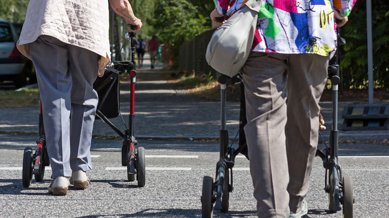 Deux femmes plus âgées utilisant un passage pour piétons avec des marcheurs