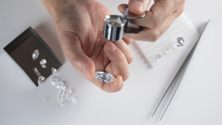 Gemmes claires maintenues en main avec la loupe et la pince à épiler